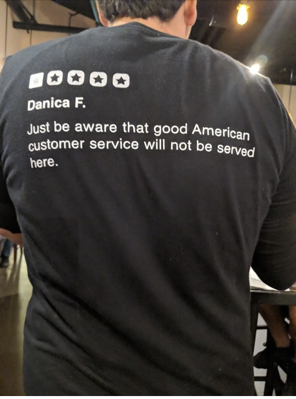A person wearing a T-shirt with a text review about customer service