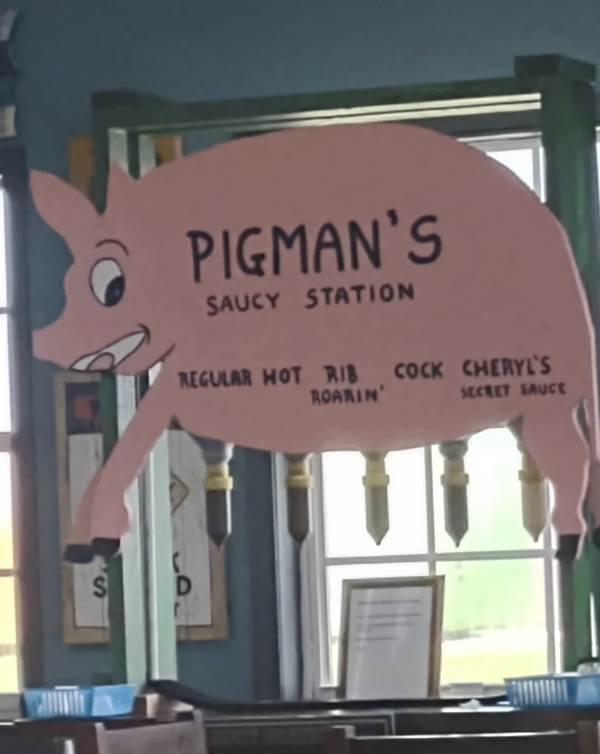 Sign with cartoon pig for "Pigman's Saucy Station" listing sauces including Regular, Hot, Rib Roamin', and Cheryl's Secret Sauce