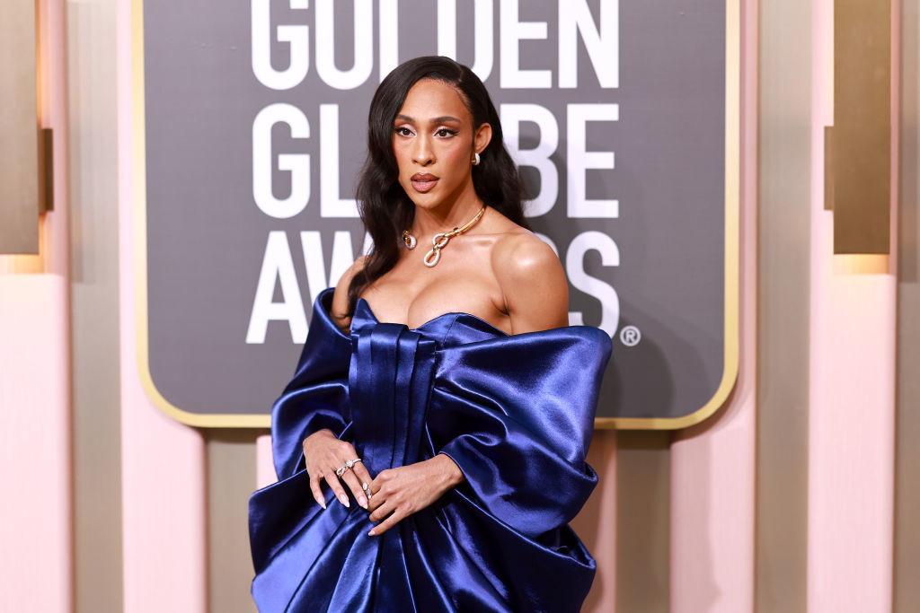 Michaela Jaé Rodriguez posing at Golden Globe Awards, wearing an off-shoulder blue satin gown with oversized bow detail