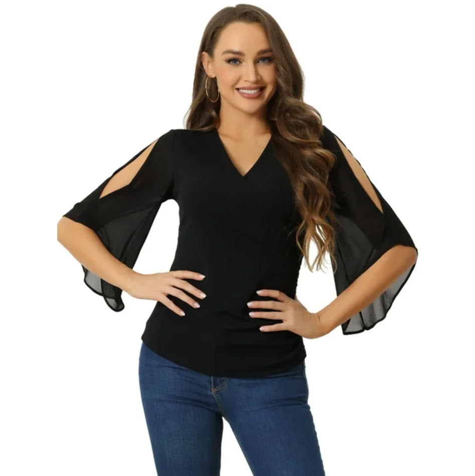 Person in a black top with shoulder cutouts and jeans, posing with hand on hip