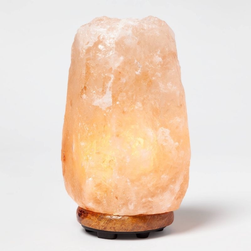 illuminated Himalayan salt lamp on wooden base, suitable for home decor and wellness