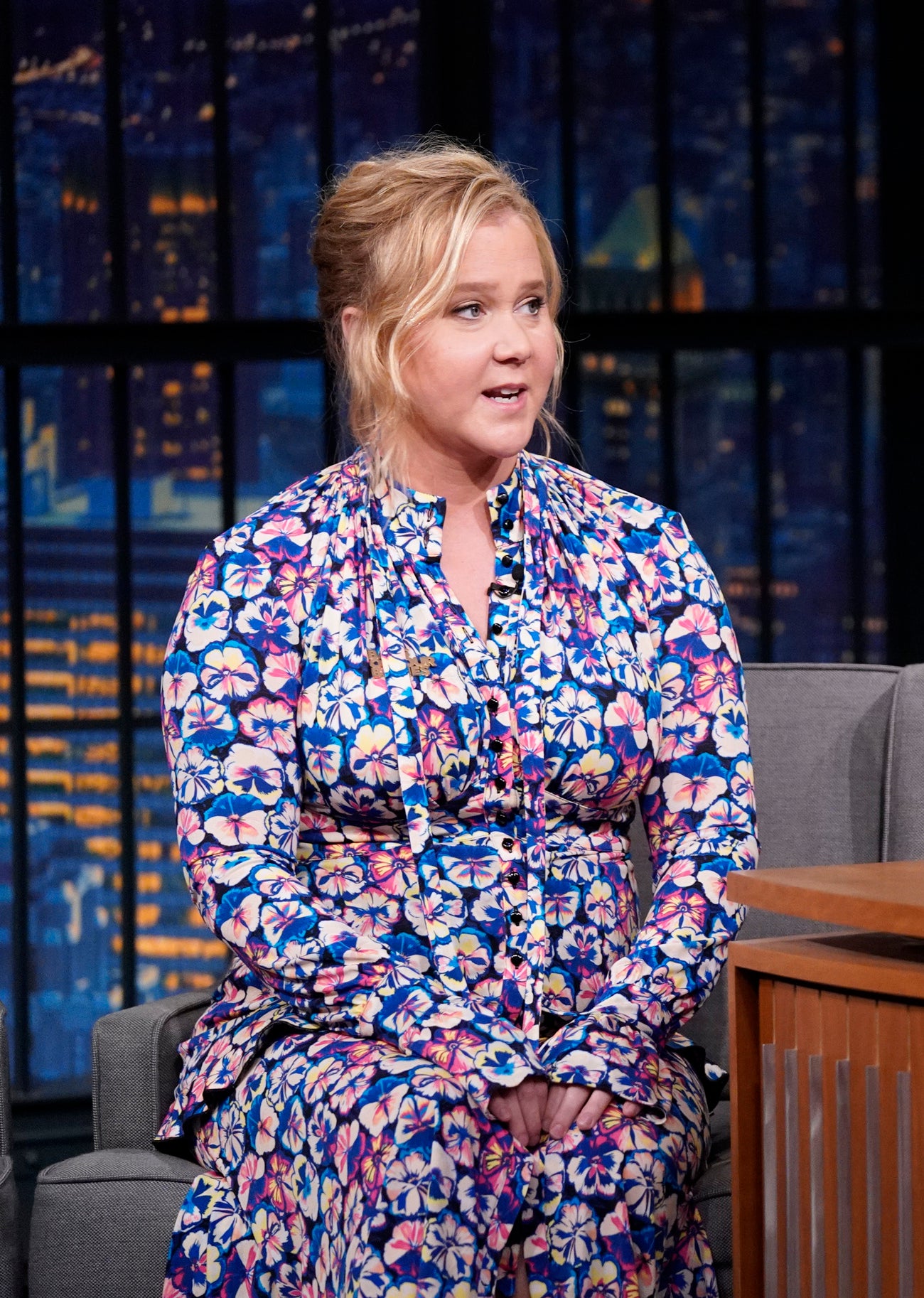 Close-up of Amy in a floral-print outfit on a talk show