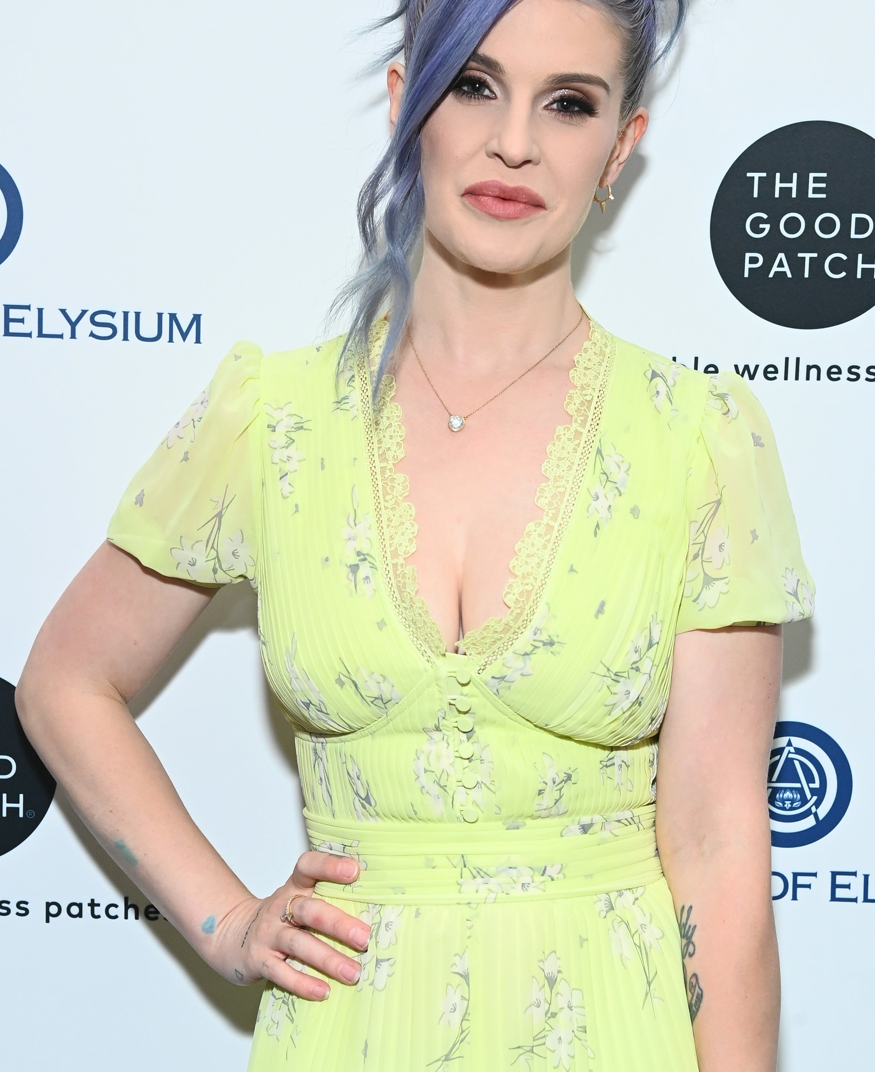 Kelly Osbourne in a yellow floral dress and with blue-gray hair, at a media event