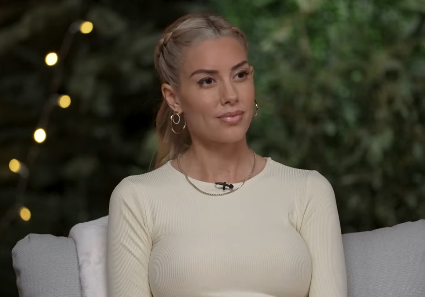 Heather Rae El Moussa on a talk show discussing co-parenting, wearing a simple crewneck top