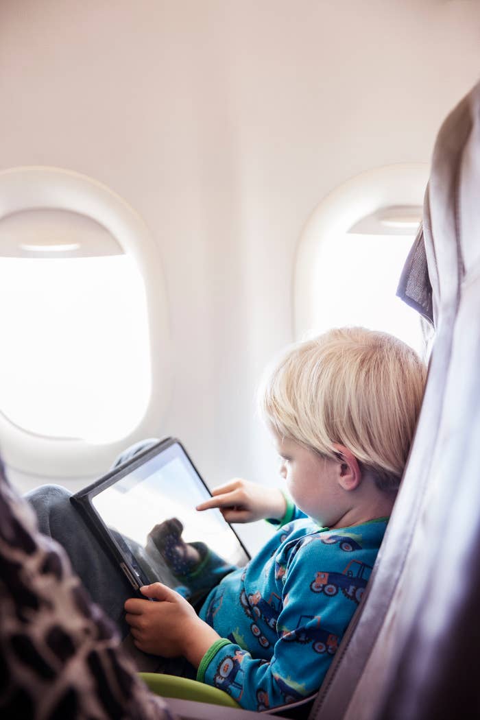 Child focused on a tablet while seated on an airplane