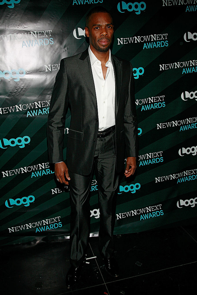 Colman in a black suit and dress shoes posing at an event with backdrop featuring &quot;Logo NewNowNext Awards&quot;