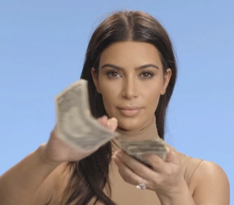 Kim Kardashian holding and fanning out several bills in her hands