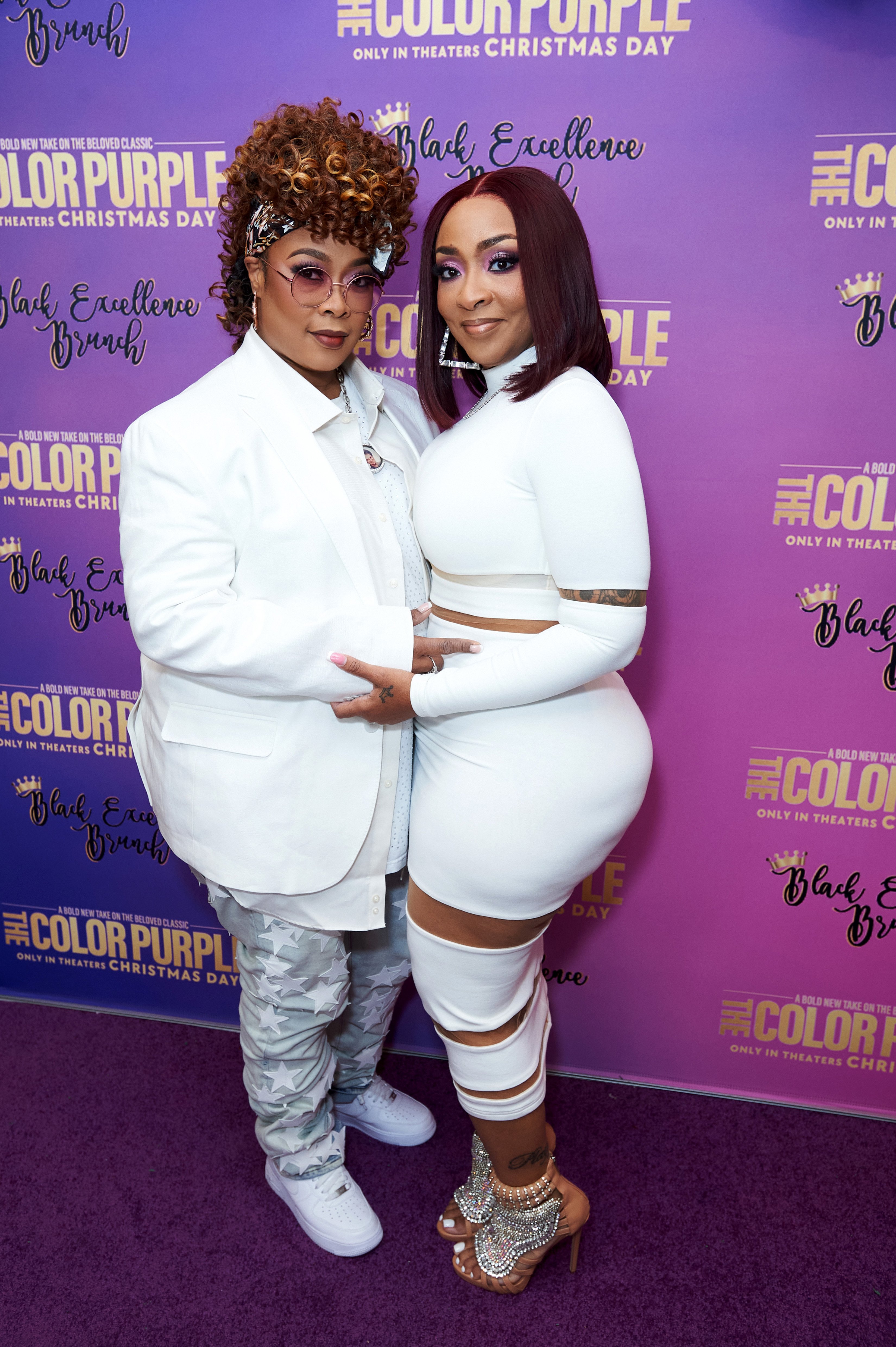 Da Brat, in a coat and camo pants, and her wife, Jesseca &quot;Judy&quot; Harris-Dupart, in a fitted white dress, posing together at a media event