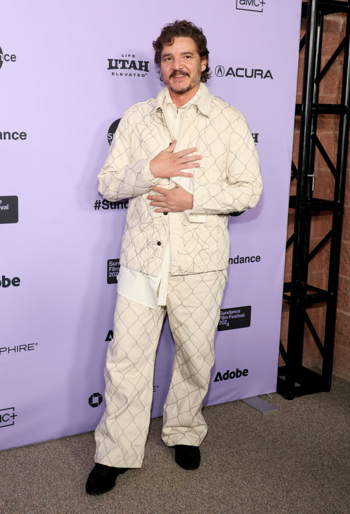 Pedro smiling and posing at an event in a patterned suit with hands crossed over his chest