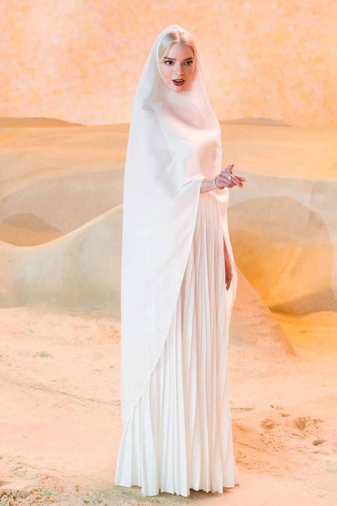 Anya in elegant white draped gown and sheer headscarf posing for a photo shoot