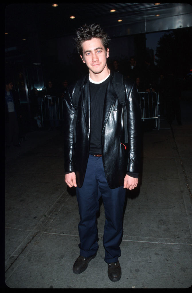 Jake in a leather jacket over a T-shirt with casual pants, standing on sidewalk