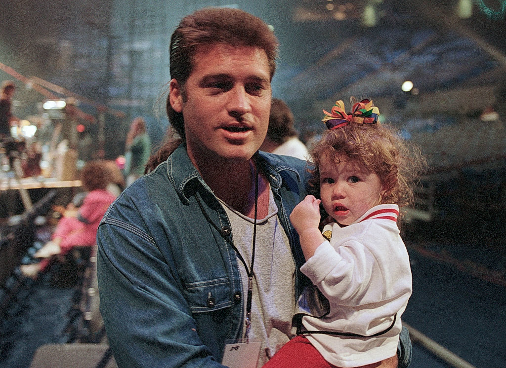 Miley being held by her father, Billy Ray Cyrus, backstage at an event