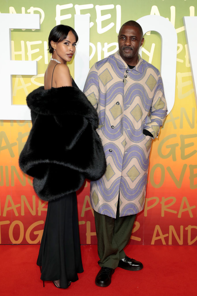 Idris is with his wife, Sabrina Dhowre Elba, on the red carpet; she&#x27;s wearing a black gown with a large fur shawl, and he&#x27;s in a patterned jacket and trousers