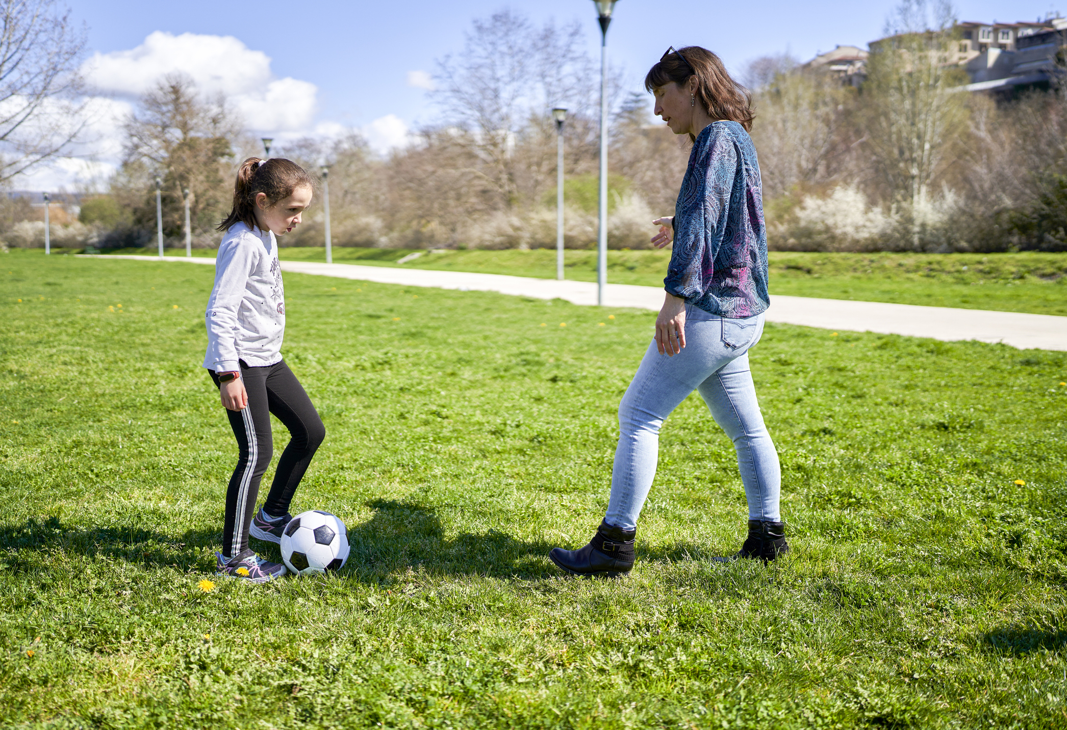 Mother and child playing soccer together in a park