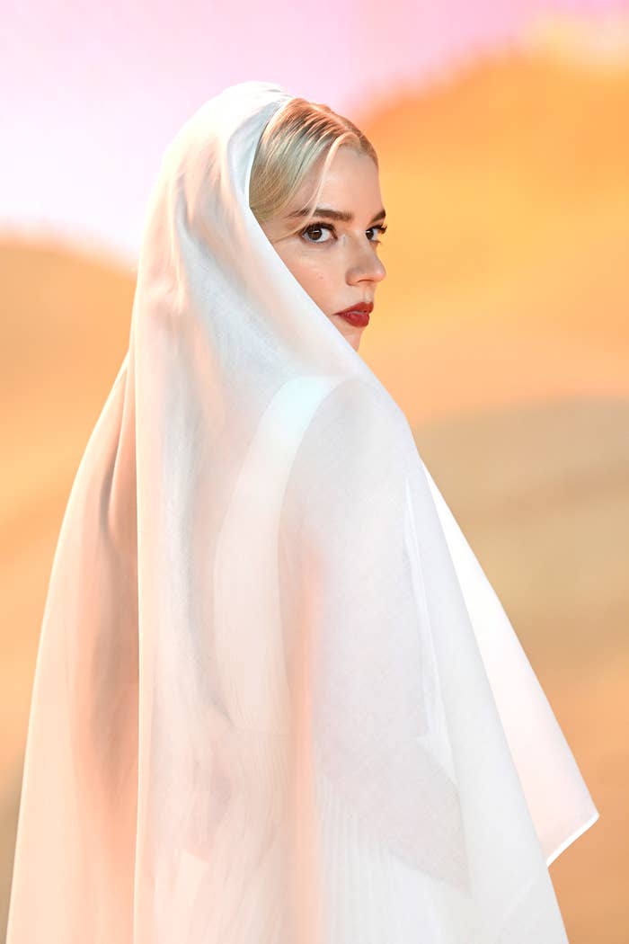 Anya shrouded in a sheer veil with a bold lipstick, gazing over shoulder