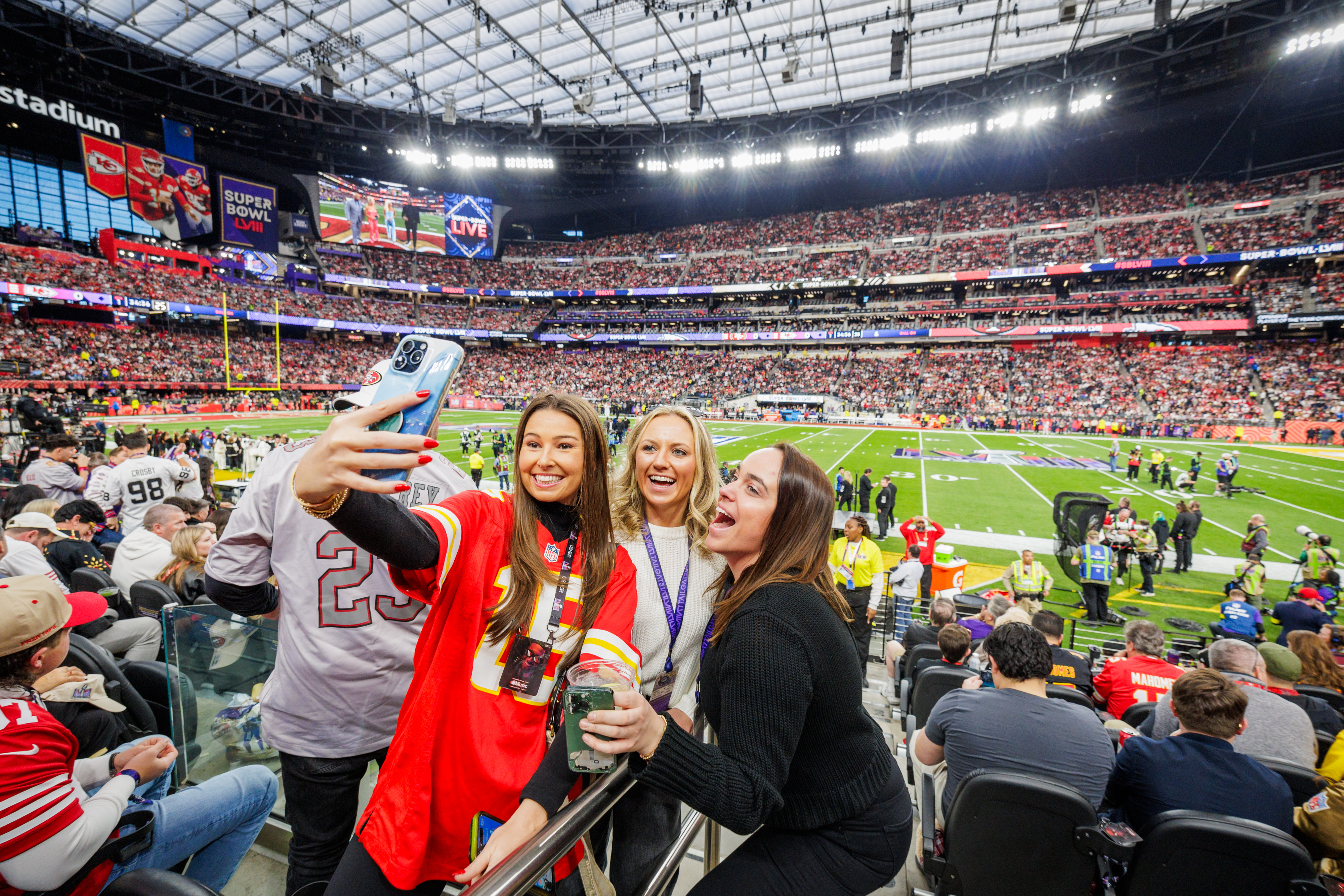 Three people taking a selfie at a packed sports stadium event