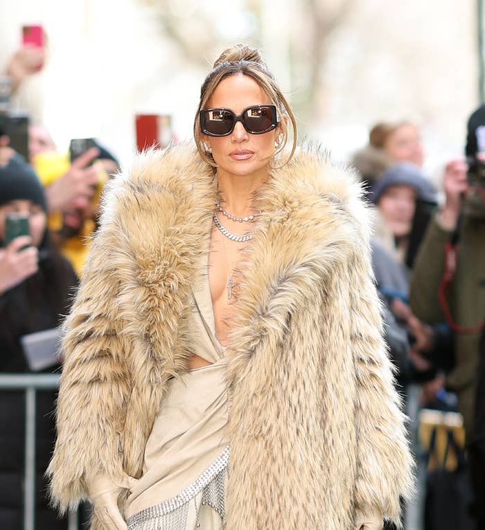 Jennifer Lopez in a luxurious fur coat and sunglasses, posing at an event