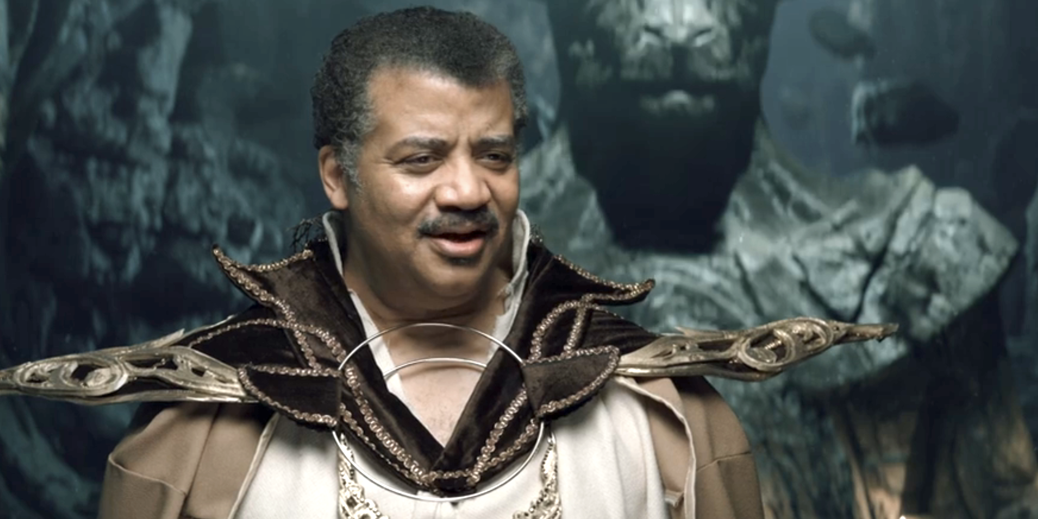 Neil deGrasse Tyson dressed in a cosmic-themed outfit with a decorative collar, on a sci-fi set