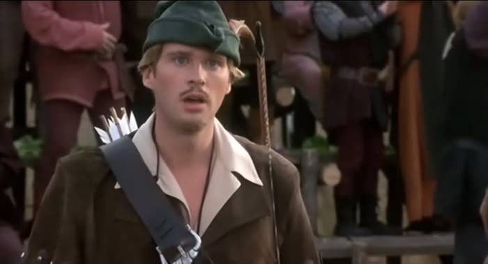 Character Robin Hood (played by Cary Elwes) looks surprised in a medieval town setting from the film
