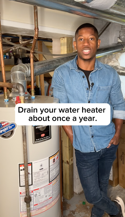 Kyshawn standing next to a water heater with text advising to drain it yearly