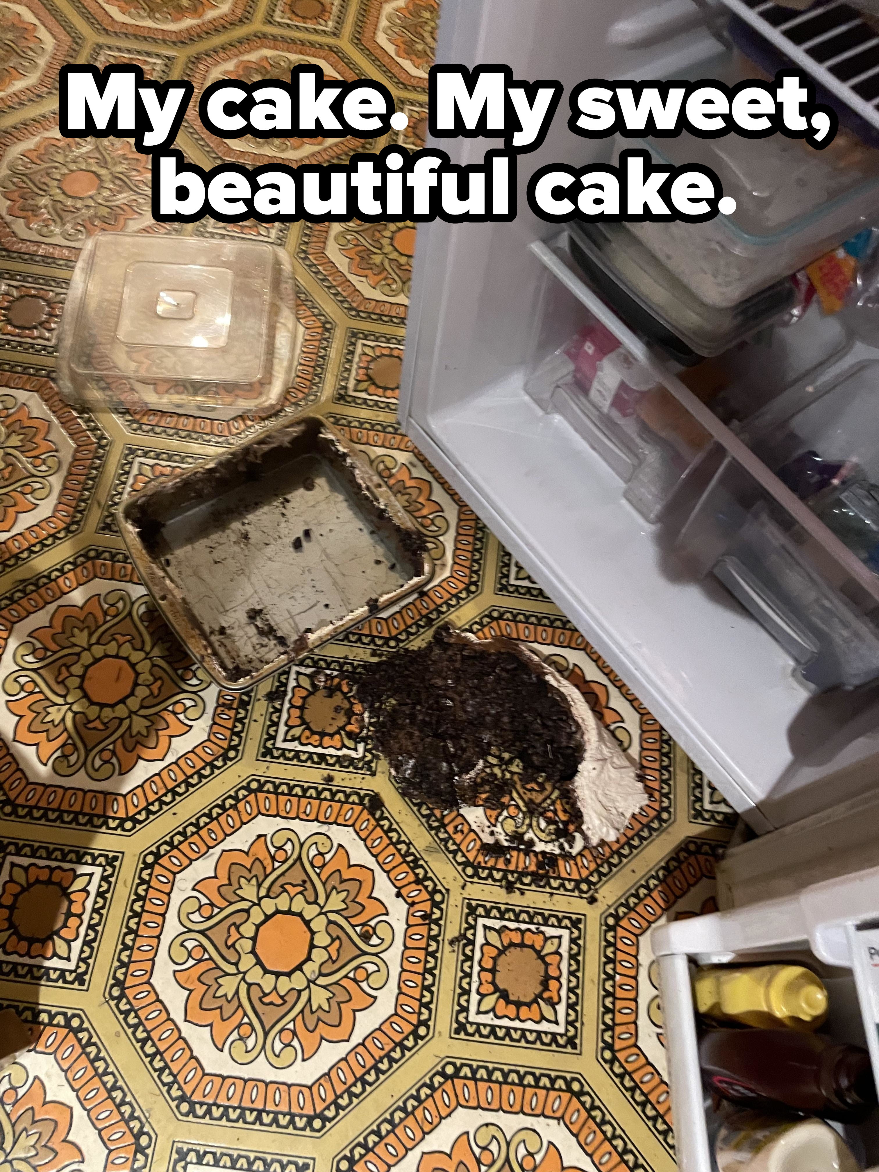 Overturned cake pan with cake scattered on a patterned floor, next to an open refrigerator with items inside