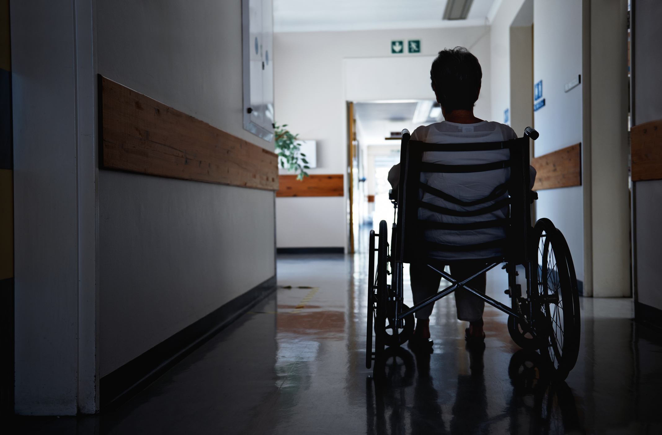 Person in a wheelchair facing a dimly lit corridor