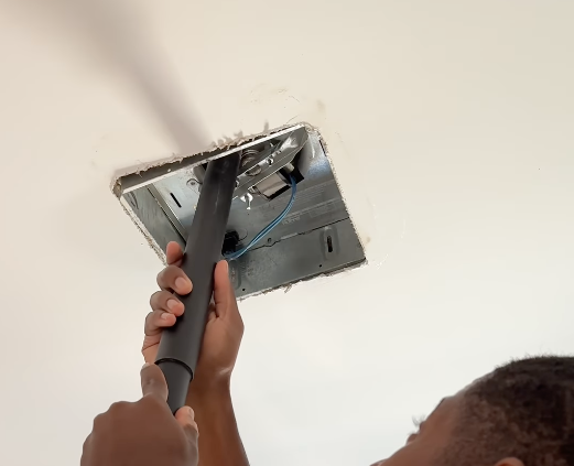 Kyshawn using a vacuum to clean an air vent
