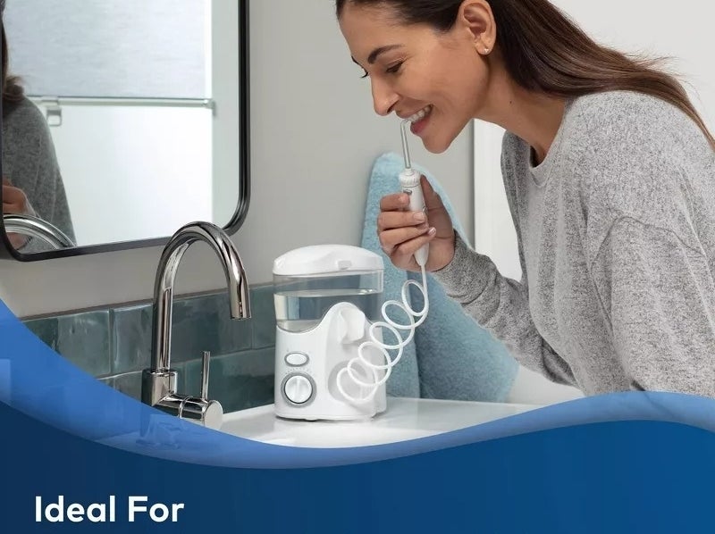 model uses a water flosser by the sink