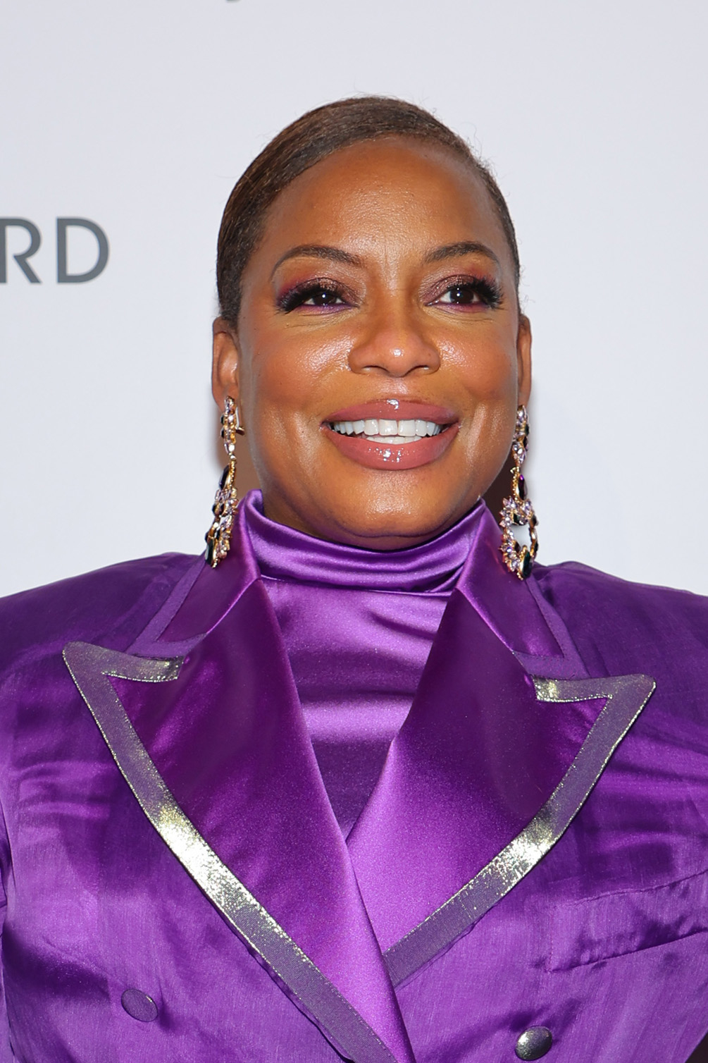 Woman in a satin purple suit with a turtleneck blouse, smiling at an event