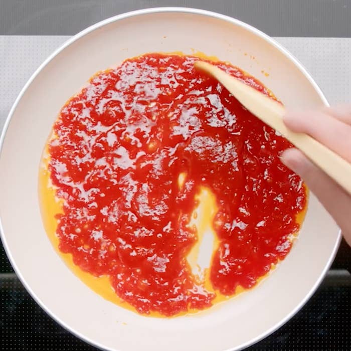 フライパンでトマトケチャップをかき混ぜる手。