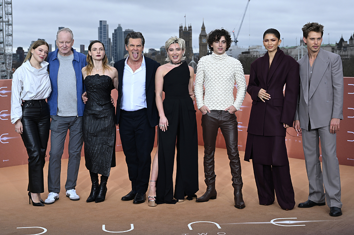 Cast of "Dune: Part Two" posing together; actors in stylish, varied formal wear on promotional event backdrop