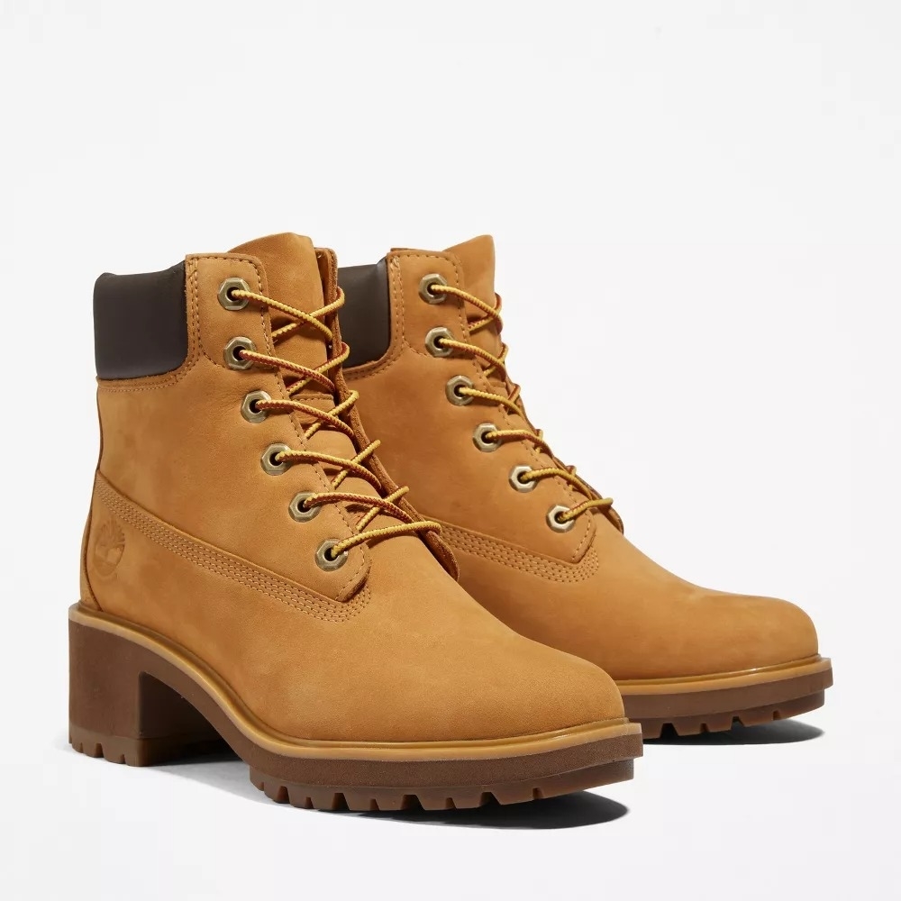 A pair of lace-up mustard colored boots with the Timberland logo on the side