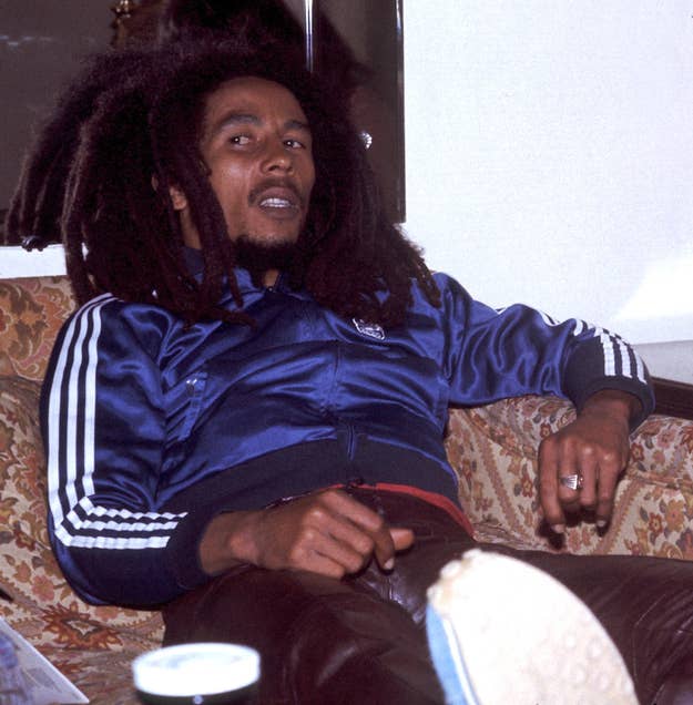 Bob Marley sitting, wearing an adidas tracksuit, with a sneaker visible