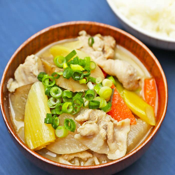 野菜と鶏肉が入った和風の煮物が盛られた丼。白米の器も添えられている。