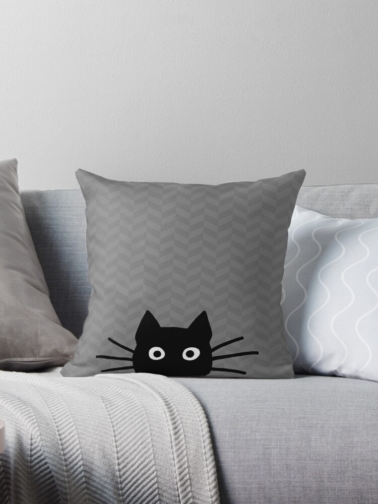 Decorative pillow with a cat face design on a chevron-patterned background, situated on a couch with other pillows