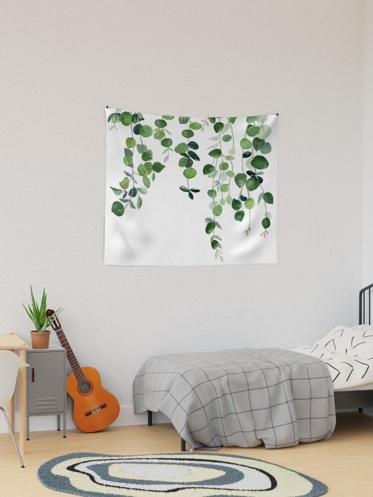 Tapestry with leaf design hanging on a wall above a bed with a guitar beside it.