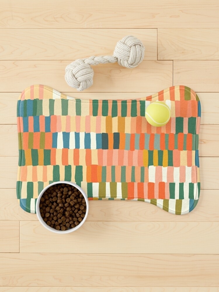 A patterned pet feeding mat with a water bowl and a food dish placed on a wooden floor