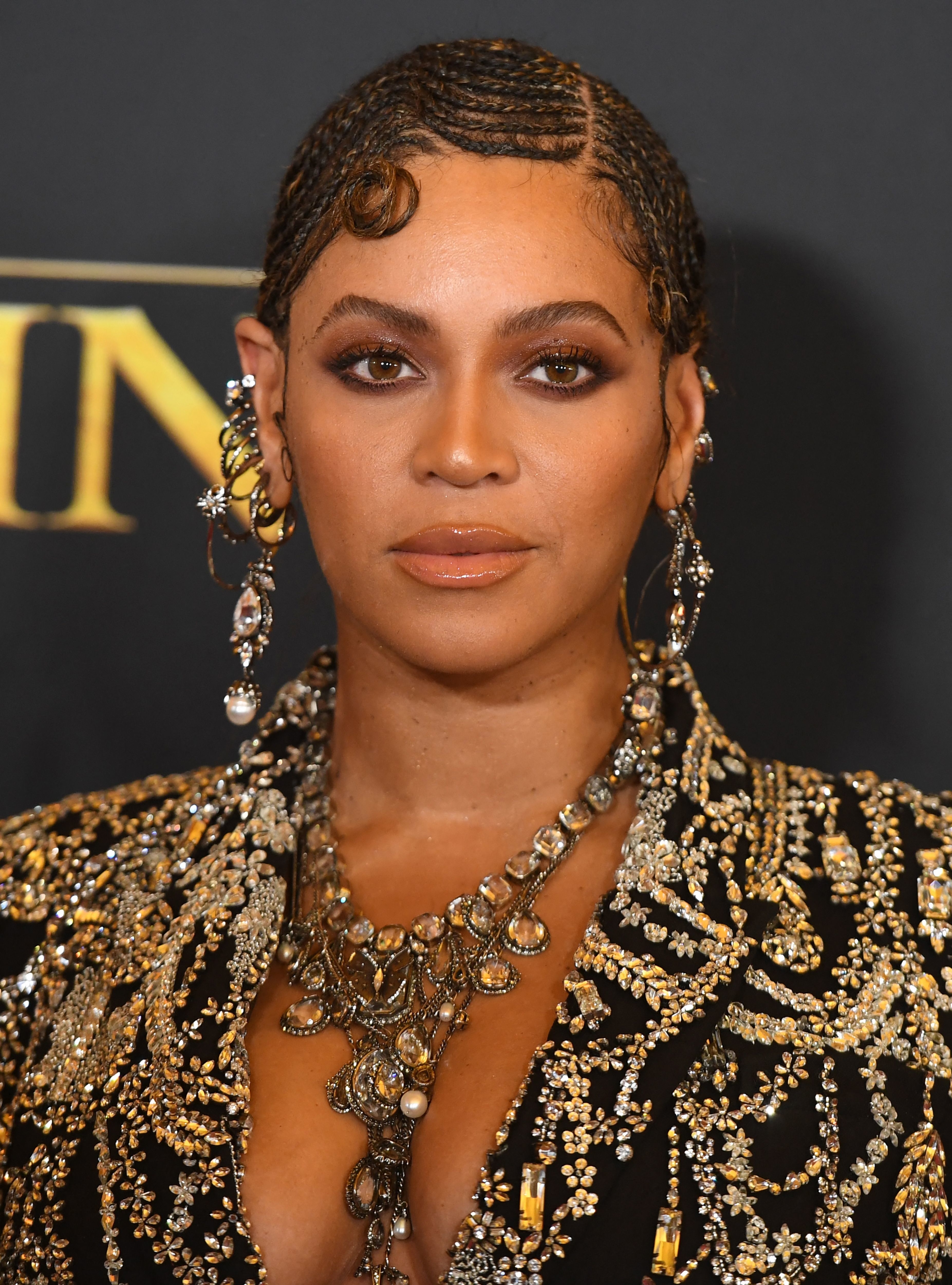 Beyoncé posing in an embellished black dress with intricate beadwork and statement earrings