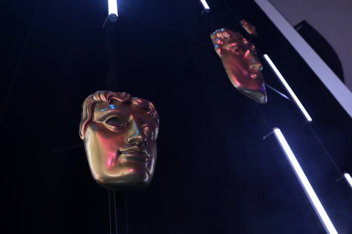 Two BAFTA masks hanging from the ceiling, illuminated by accent lighting
