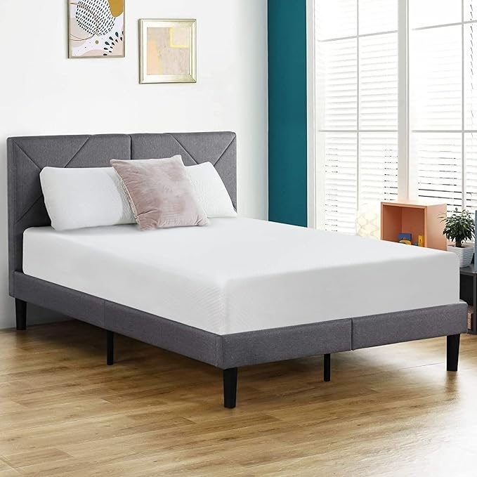 A modern upholstered bed with a white mattress in a stylish bedroom setup