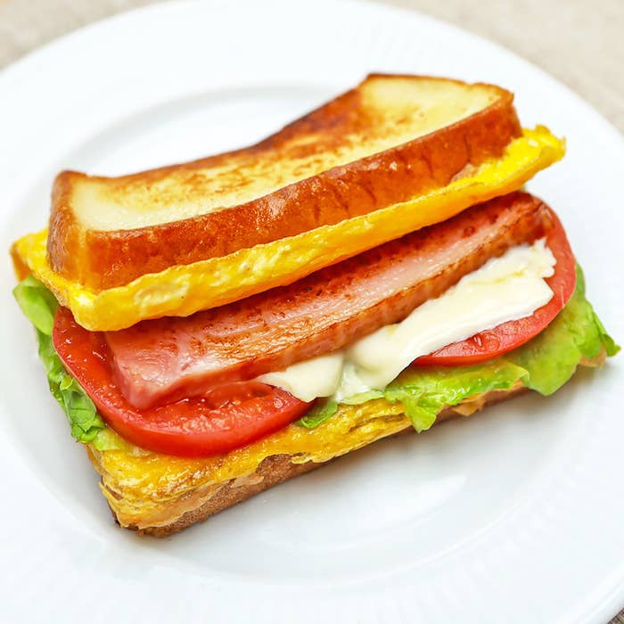 サンドイッチにレタス、トマト、ベーコン、卵、マヨネーズが挟まれている。