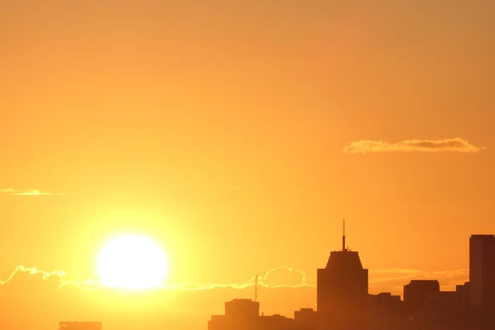 Sun setting behind a city skyline with clear skies