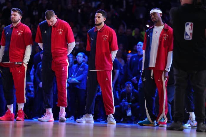 Four basketball players in red tracksuits standing on the court