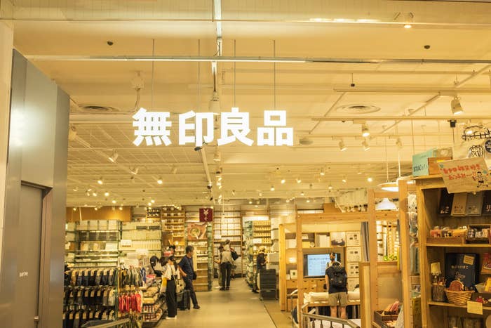 照明が明るい室内の雑貨店で、商品が並び買い物をする人々がいる。