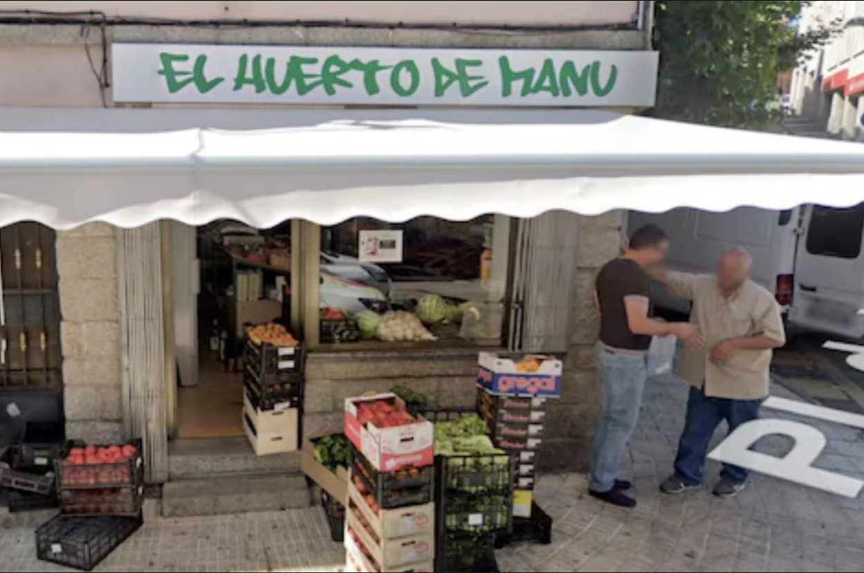 Two people stand outside a store named 'El Huerto de Hanu', with fresh produce on display