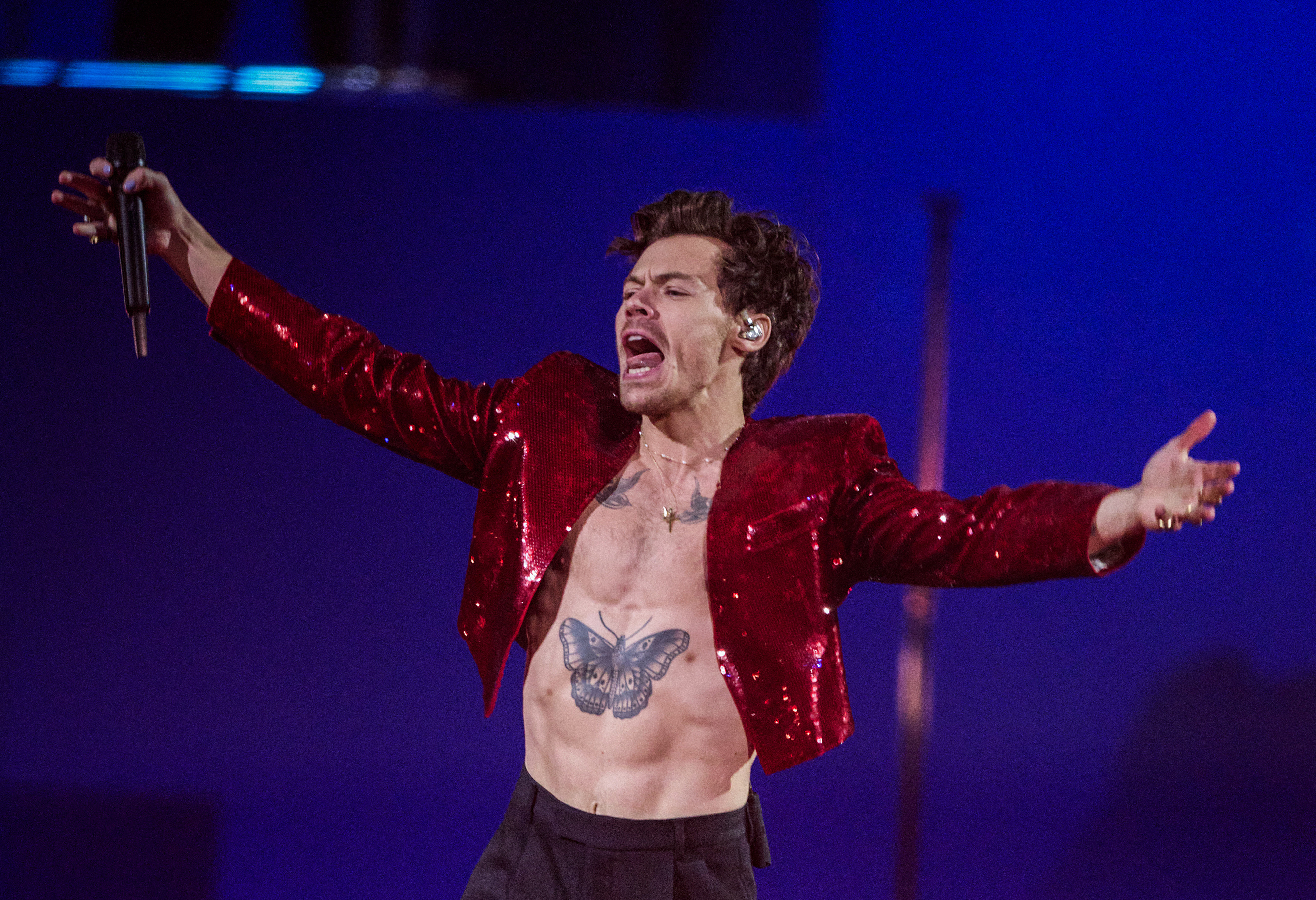 Harry Styles performing in a shiny crop jacket