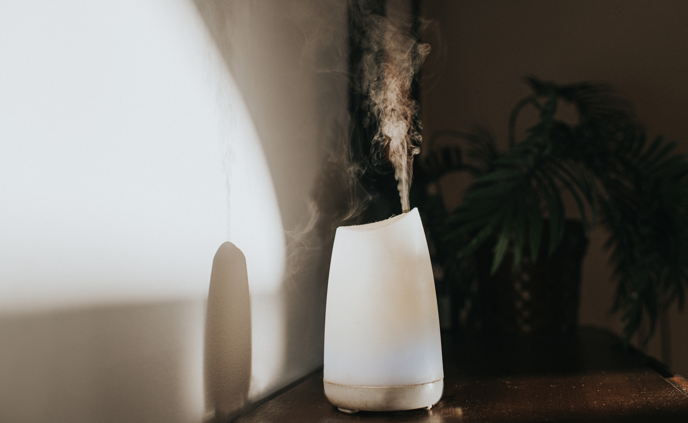 A simple white oil diffuser spritzing a light mist of water and aromatherapy blended oils into the air