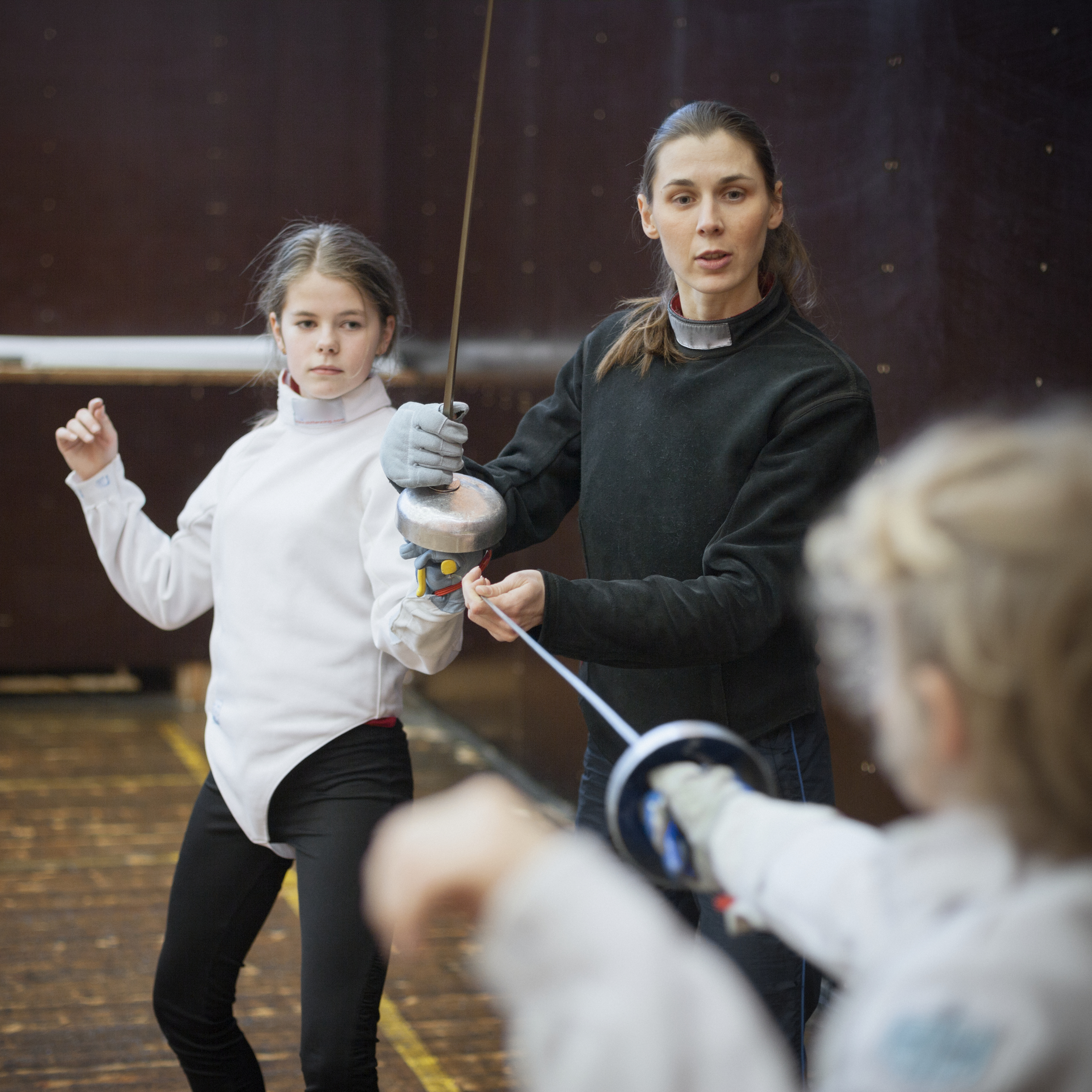 A woman leading a fencing lesson