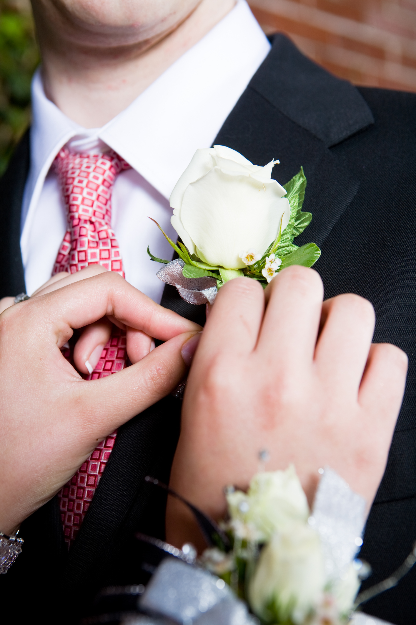 a person fastening a flower on a man&#x27;s lapel