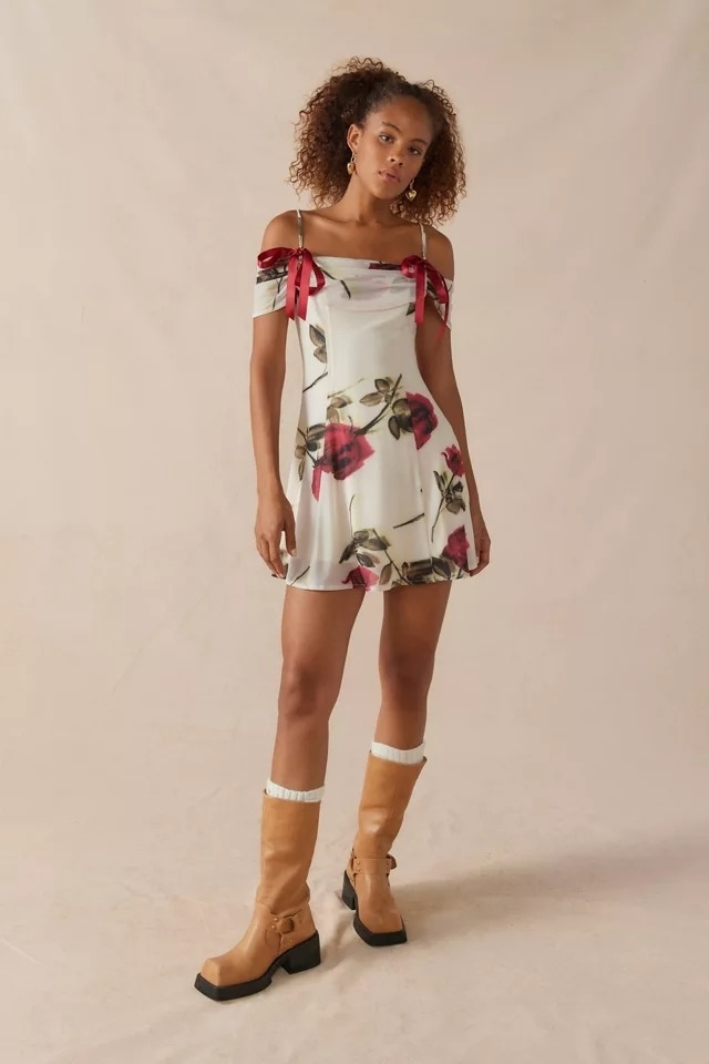 model wearing cold shoulder mini dress with rose and white design